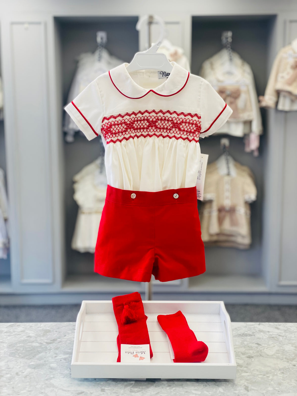 NAXOS Pablo boys red short set with ivory hand-smocked shirt, red piping and tailored red shorts & coordinating socks.