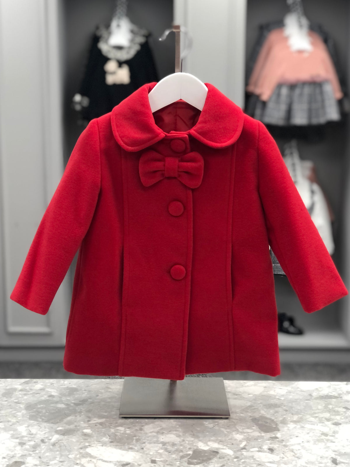 Eva Class Valeria girls red traditional coat front view with rounded collar, matching bow and fabric-covered buttons