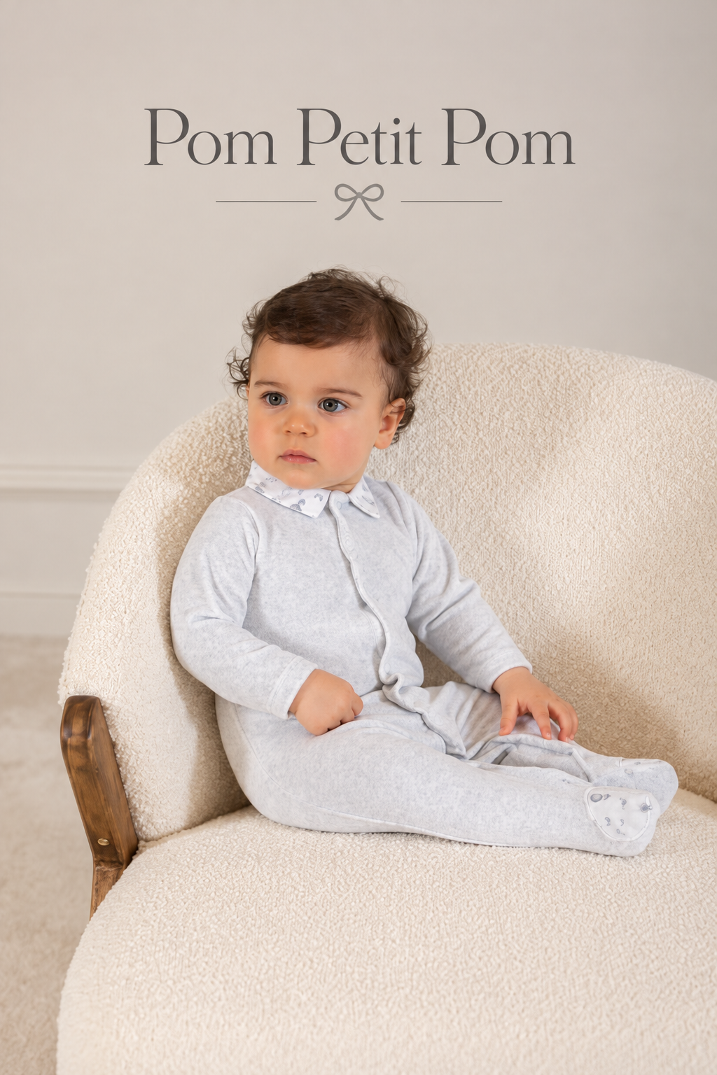 Pom Petit Pom collection cover featuring a baby in a grey velour babygrow with elegant brand lettering