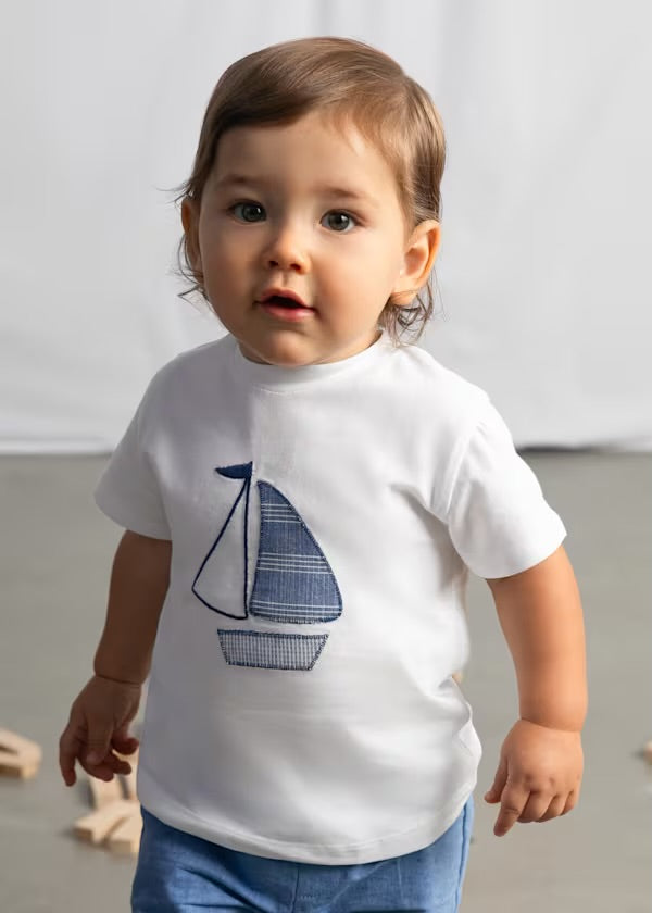 Toddler boy modelling the Mayoral sailboat T-shirt and blue trousers
