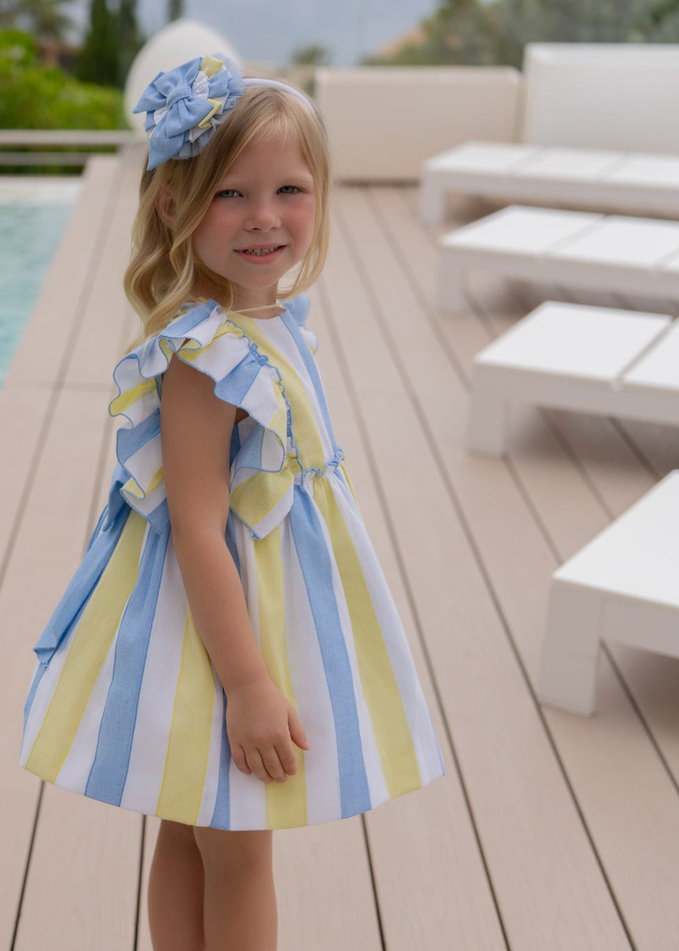 Girl wearing the Miranda Blue & Yellow Stripe Girls Headband featuring a layered blue, yellow and white striped bow with delicate tulle detailing.