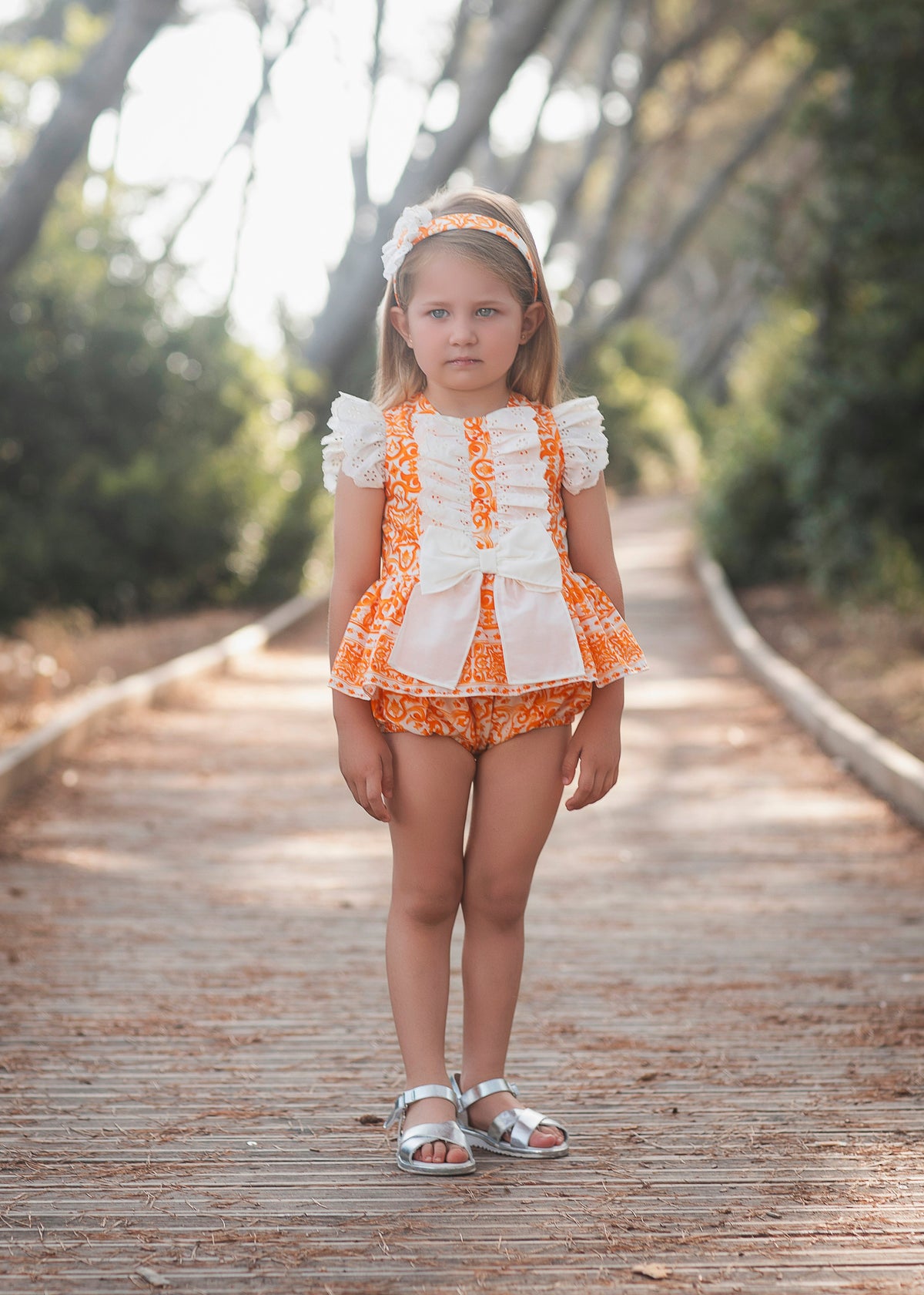 Rochy Majolica girls orange tile print one-piece peplum romper with white broderie anglaise ruffles and bow