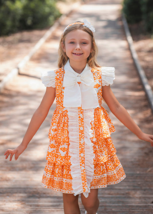 Rochy Majolica girls orange and white tile print dress with broderie anglaise ruffles and statement bow