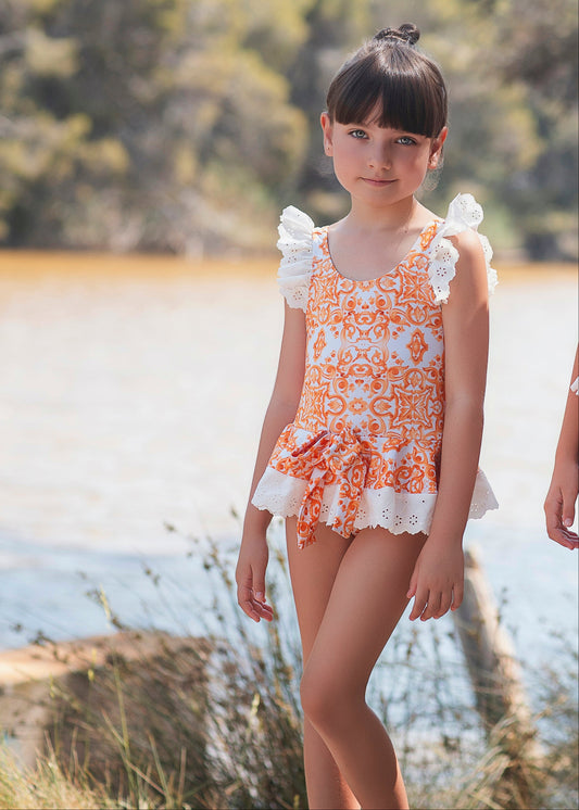 Rochy Majolica girls orange tile print swimsuit with white broderie anglaise frills - front view