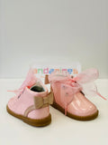 A pair of pink patent leather ankle boots for girls with a bow and trim to the heel, pink tulle laces, and a spare pair of pink cord laces.