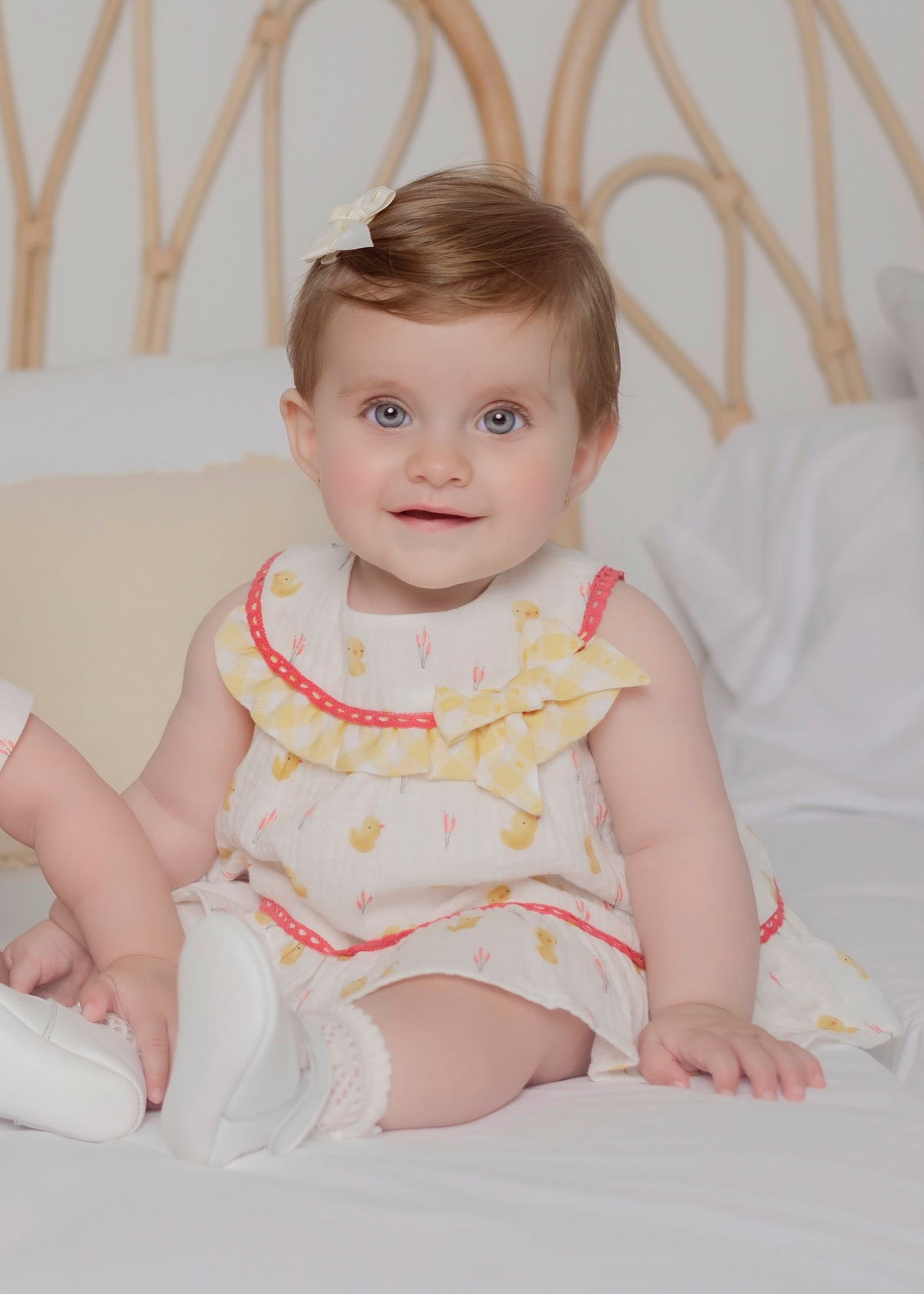 Baby girl wearing Miranda Little Chick lemon cotton muslin dress with chick print, gingham frill and bow