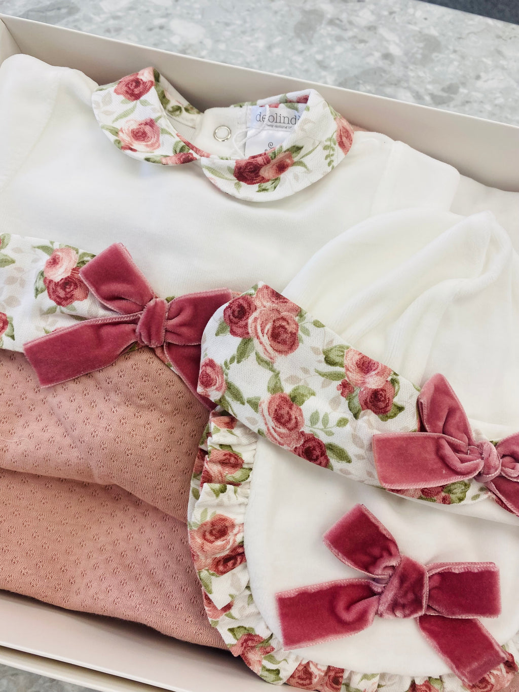 Floral baby outfit with pink bows in a box