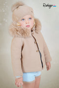 Child wearing Rahigo camel double-ply knitted children's coat with plush faux fur lining, button fastening and detachable real fur trimmed hood, made in Spain.