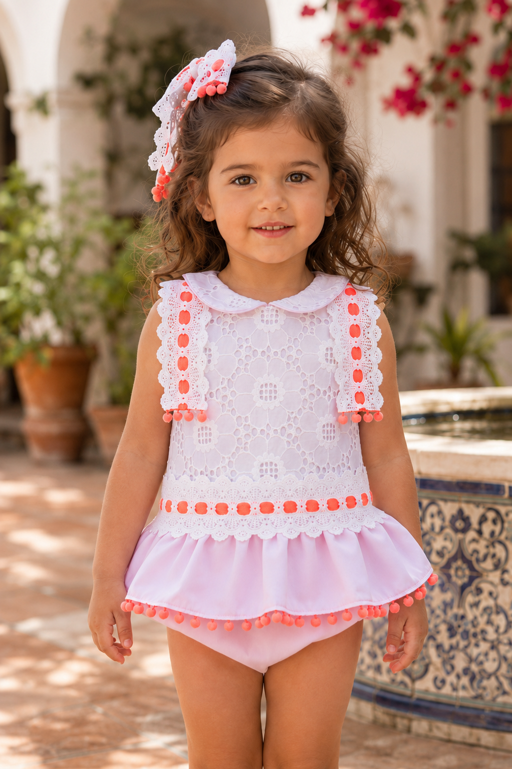 Naxos Neon girls pink dress and knickers showing white lace back, button fastening and orange pom pom trim.
