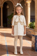 Girl wearing the Naxos cream and gold bouclé tweed dress in a Spanish courtyard