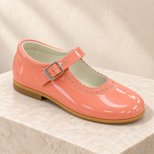 Andanines coral pink patent leather girls Mary Jane shoes with scalloped detail and buckle strap.