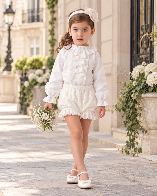 Rochy Blonda girls cream jam pant set with a white ruffle blouse and cream lace jam pants, styled on a little girl in an elegant Parisian courtyard.