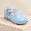 Andanines blue patent leather boys T-bar shoe on a cream stone plinth
