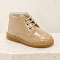 Andanines camel patent leather boys lace-up boots on a warm ivory studio background