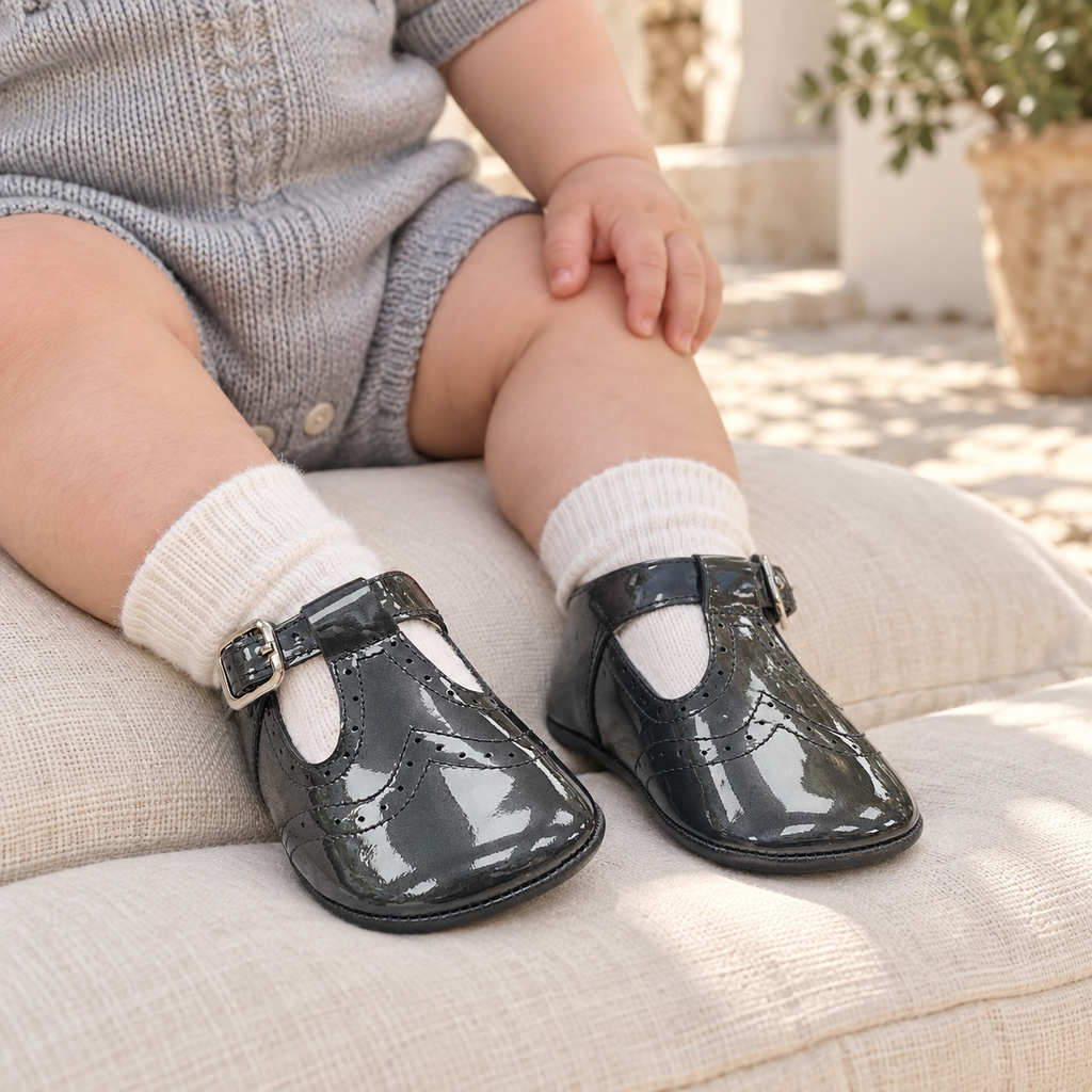 Andanines charcoal grey patent leather baby boys T-bar pram shoes worn with ivory socks