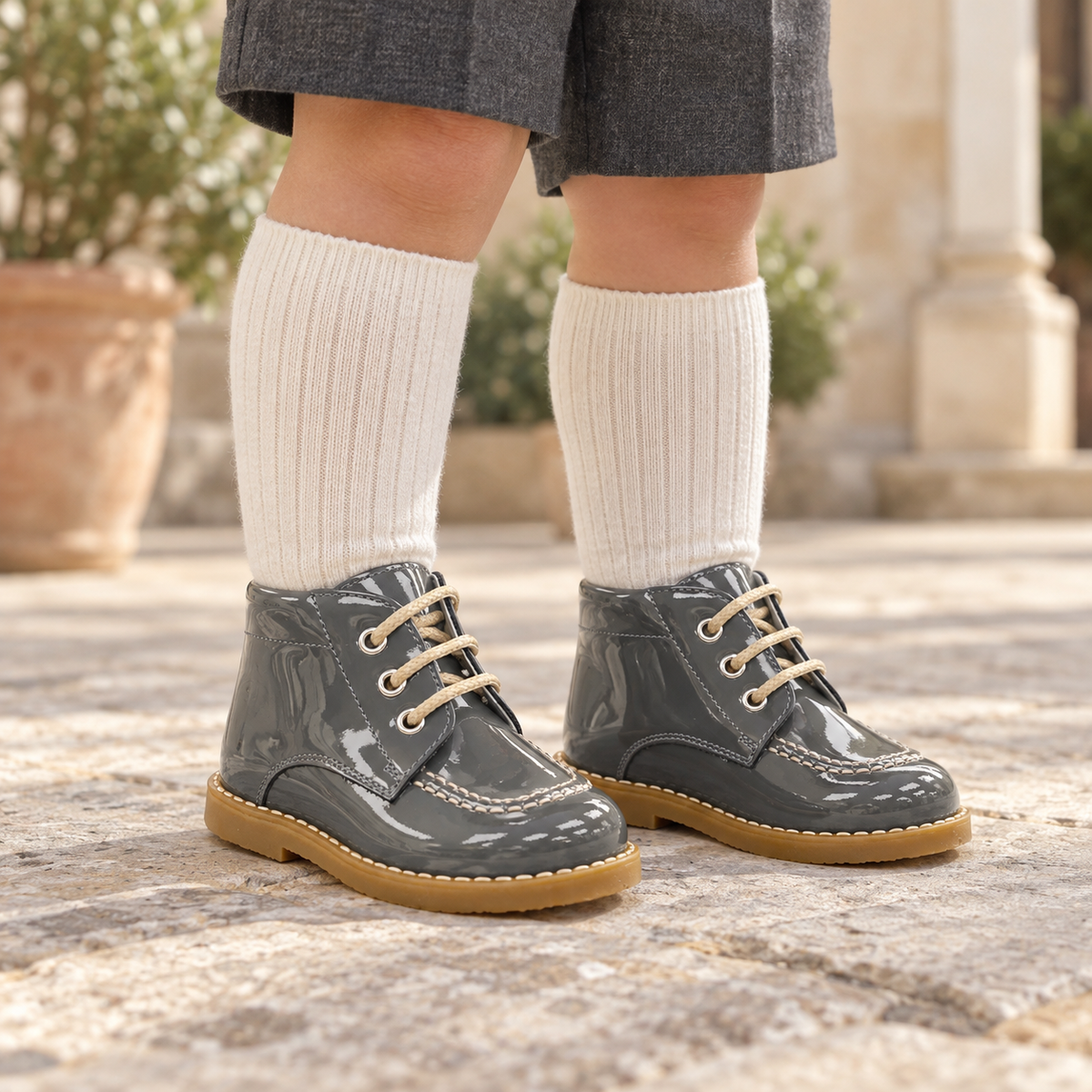 Andanines grey patent leather boys lace-up boots worn with grey shorts and ivory knee-high socks