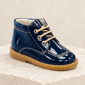 Andanines navy patent leather boys lace-up boots on a warm ivory studio background