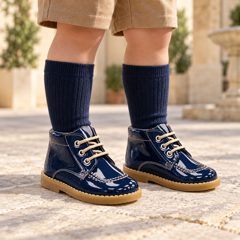 Andanines navy patent leather boys lace-up boots worn with camel shorts and navy knee-high socks