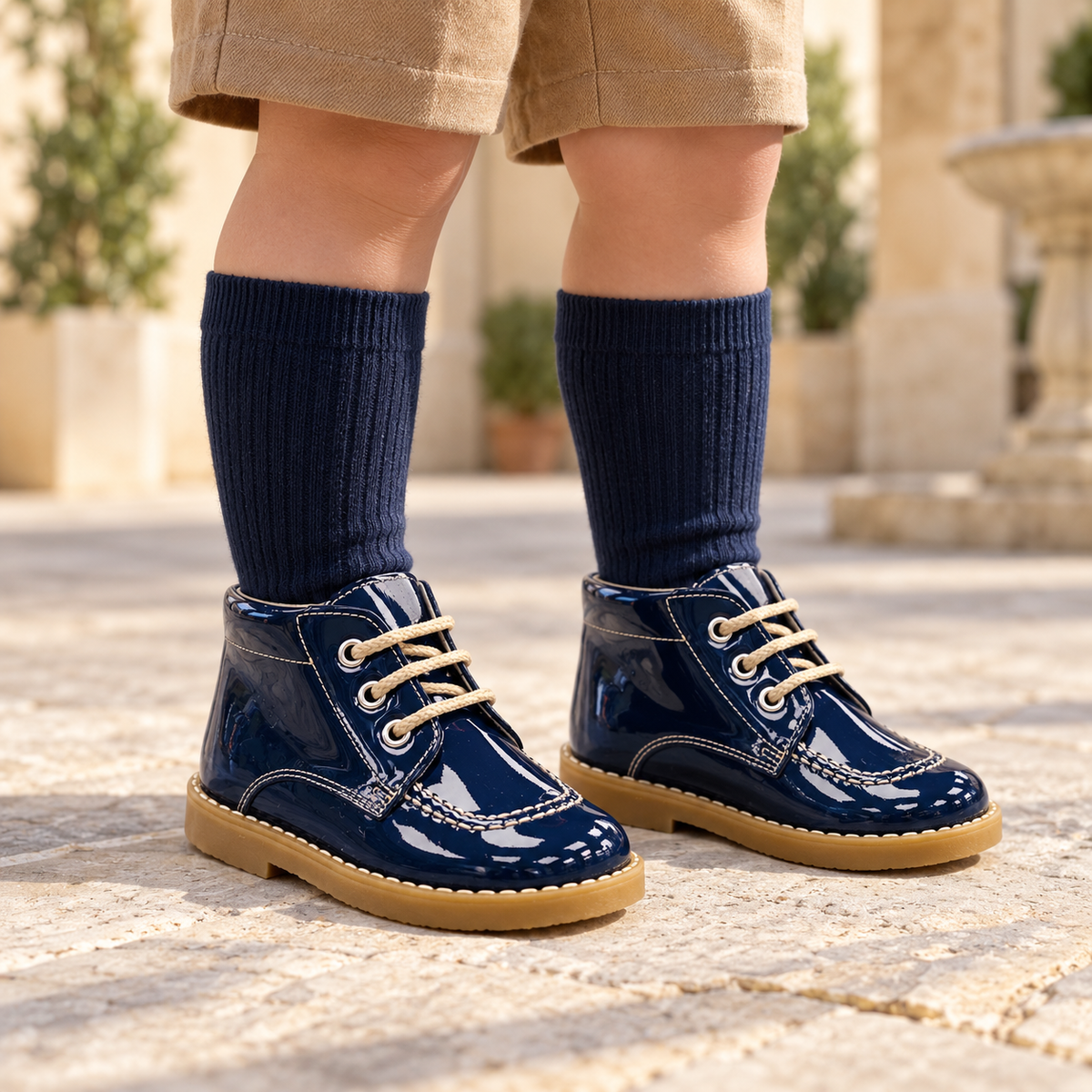 Andanines navy patent leather boys lace-up boots worn with camel shorts and navy knee-high socks