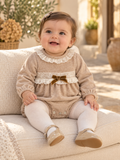 Baby girl wearing the Babine beige velour romper with ivory lace and velvet bow