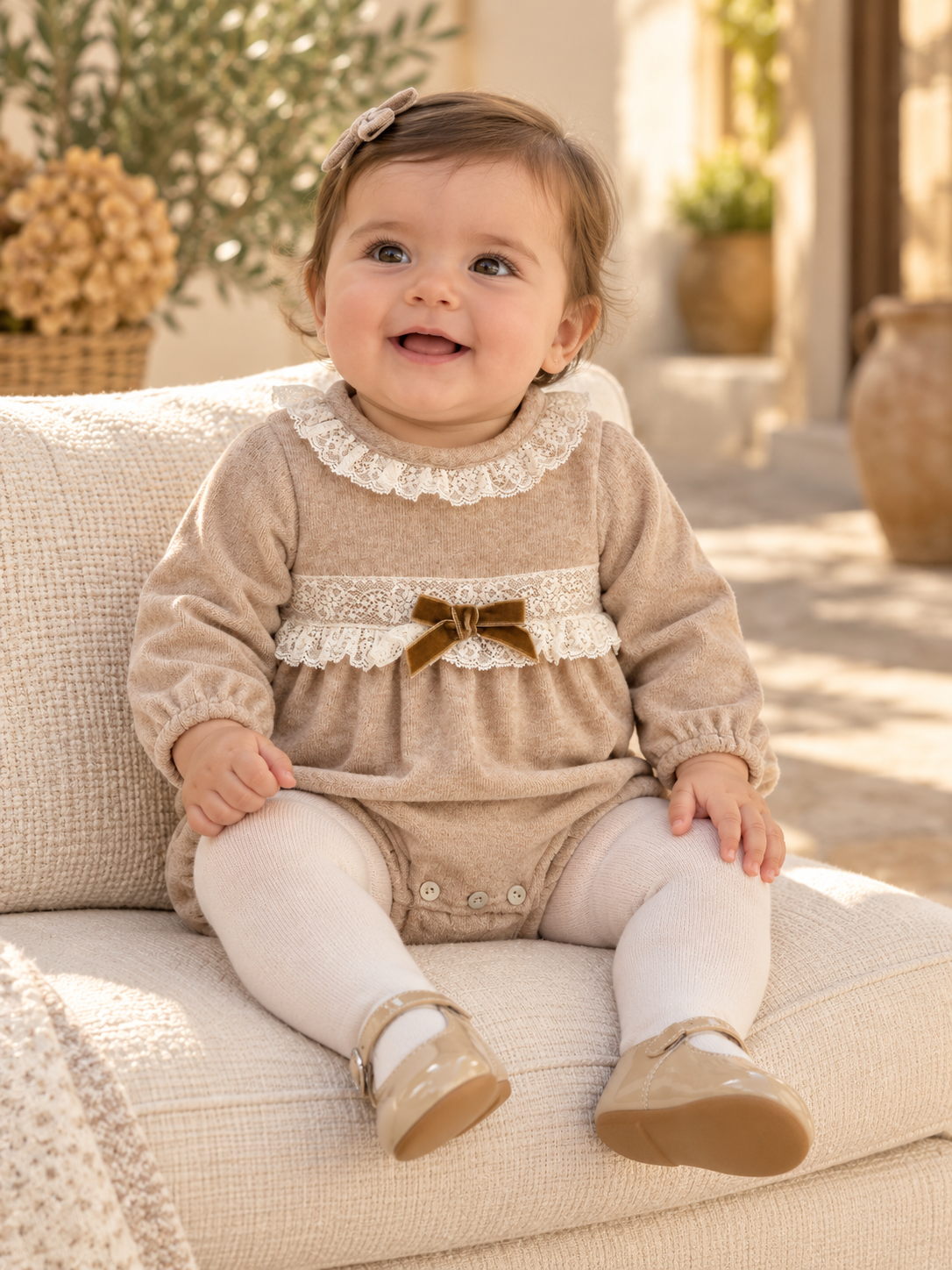 Baby girl wearing the Babine beige velour romper with ivory lace and velvet bow