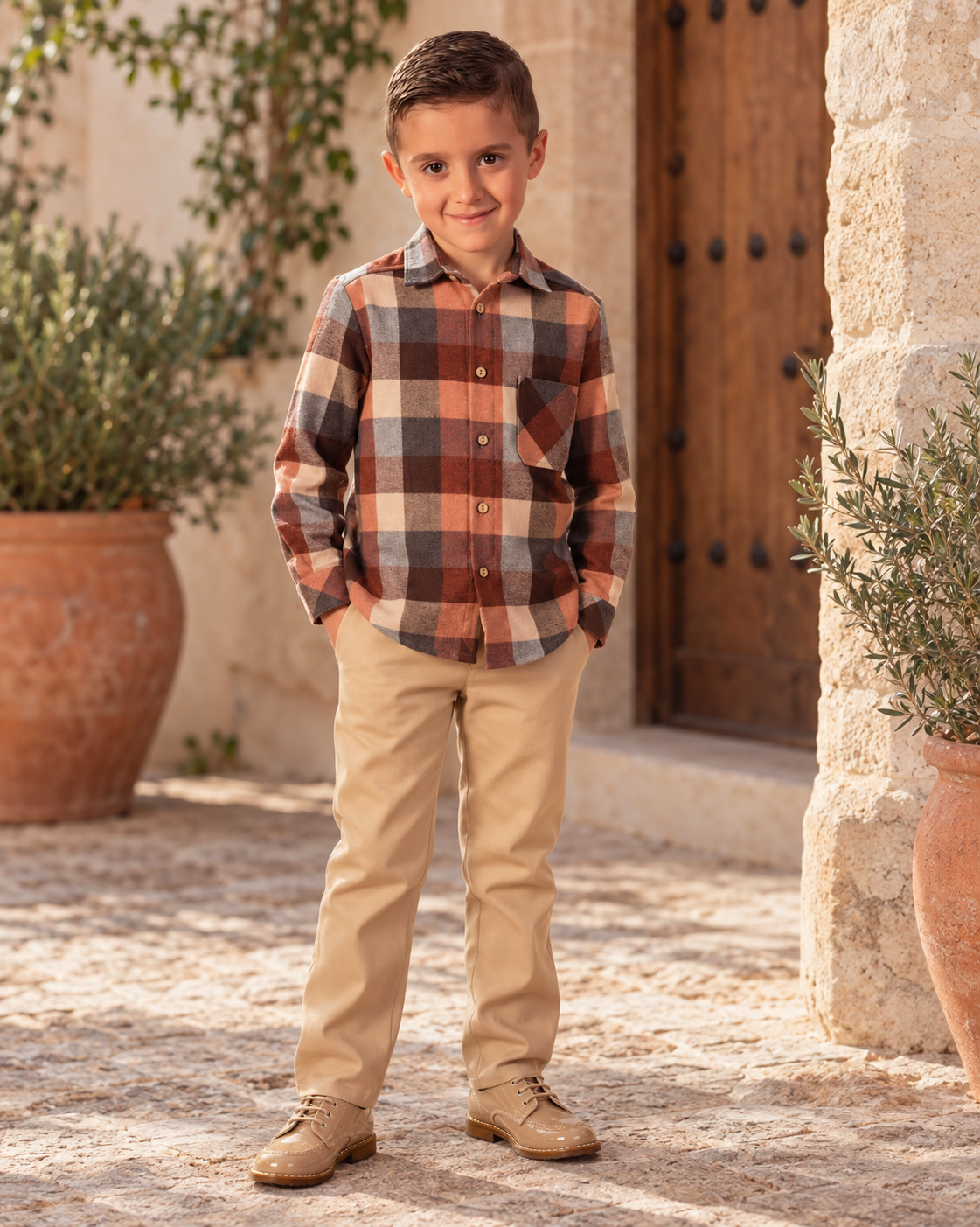 Boy wearing the Babine Calabaza camel and brown check trouser set in a Spanish courtyard