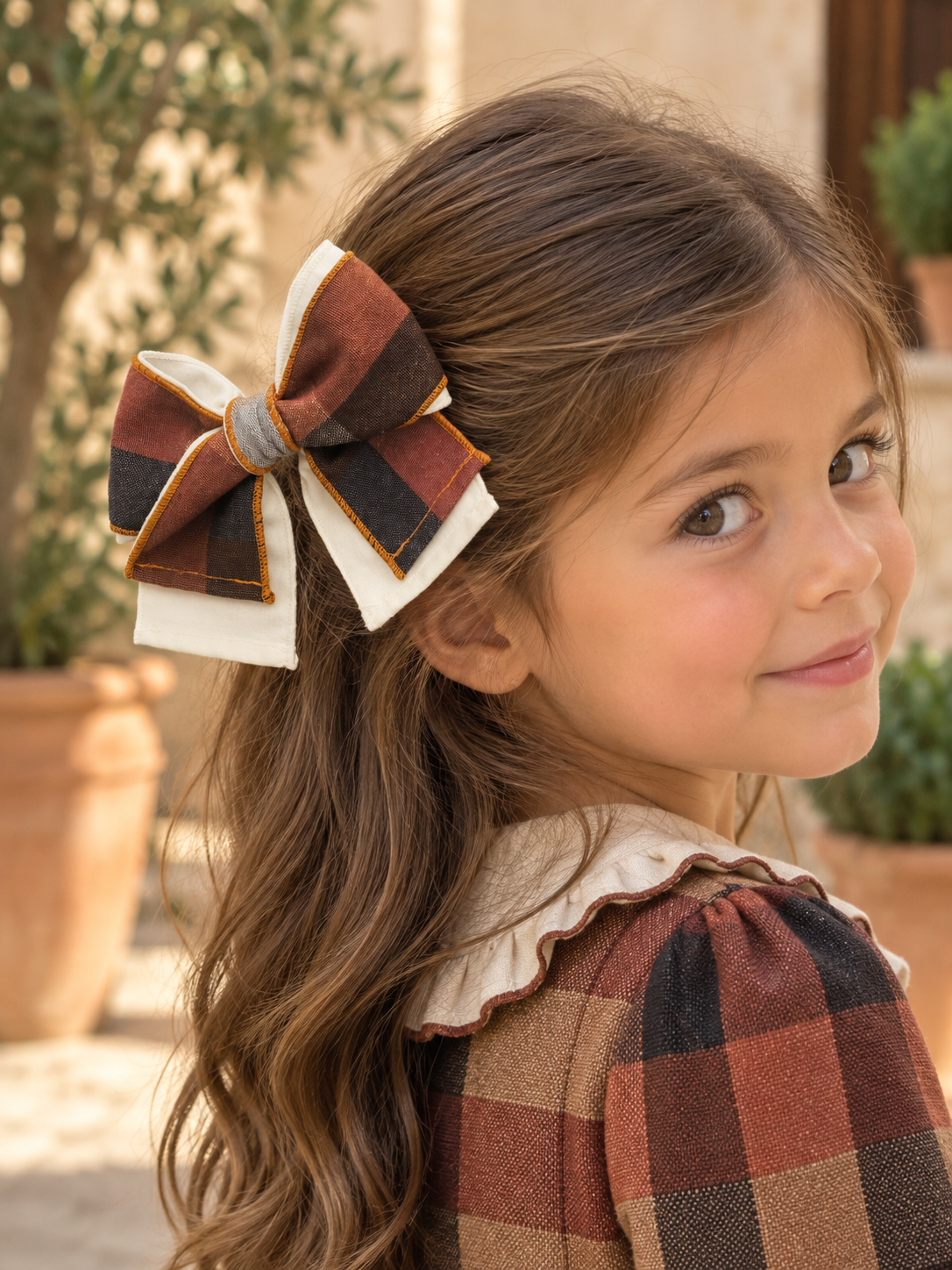 Girl wearing the Babine Calabaza camel and brown checked hair bow