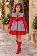 Girl wearing the Babine red check puffball dress in a festive Spanish street