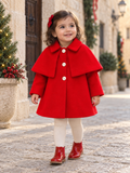 Little girl wearing the Babine red girls cape coat in a festive Spanish street