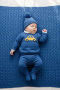 Baby boy lying on blue knit blanket in car outfit