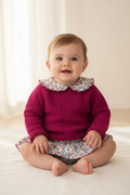 Baby girl in fuchsia knit and floral bloomer skirt