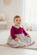 Baby girl in fuchsia knit and floral liberty dress