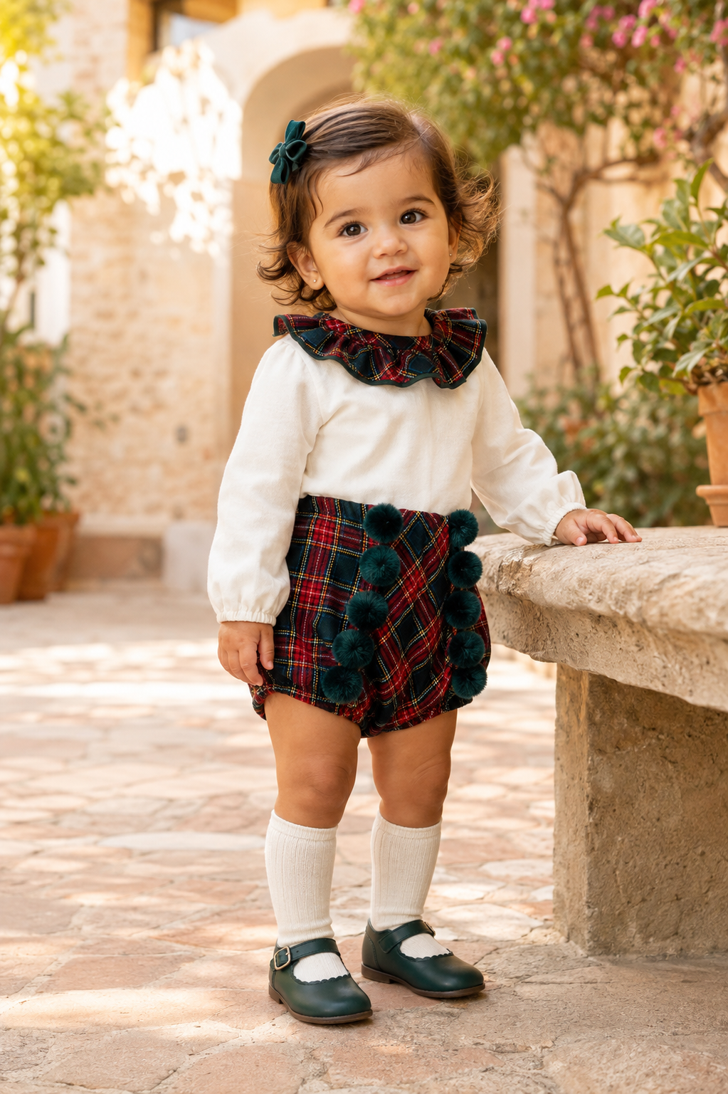 Baby girl wearing the Calamaro Galerna tartan blouse and pom-pom jam pants, three-quarter view
