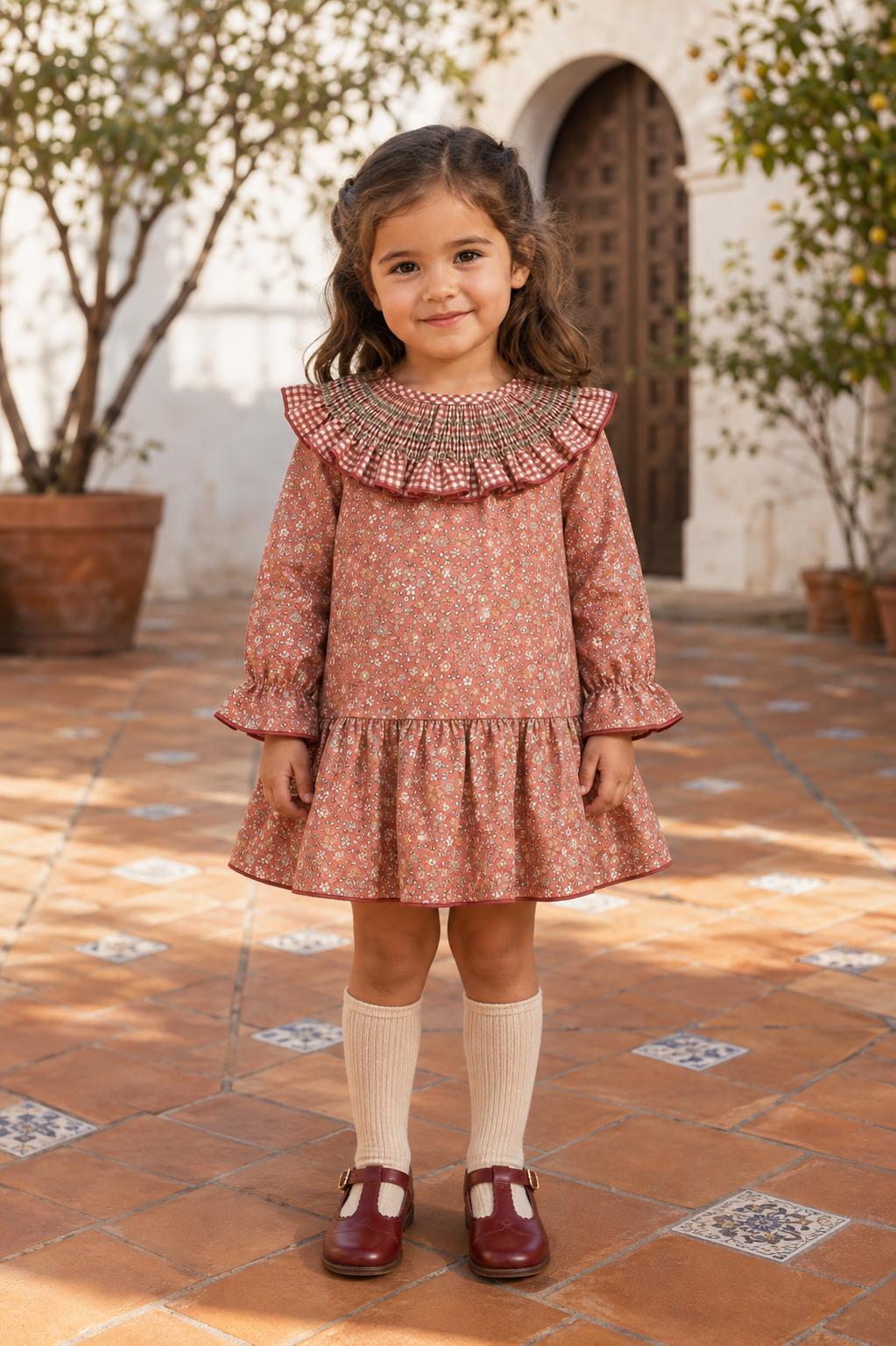 Calamaro Siroco terracotta floral dress on a girl in a Spanish courtyard, front view