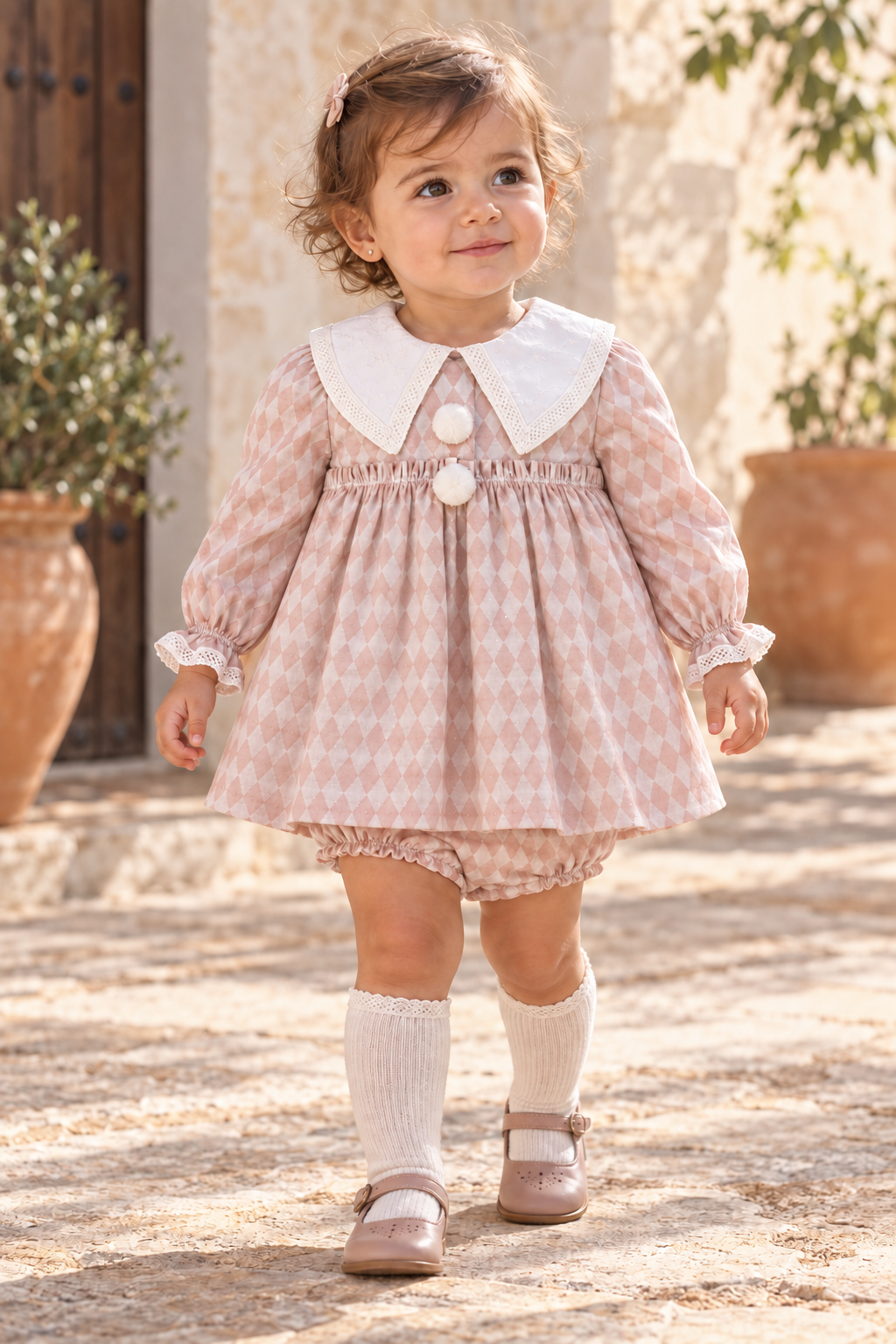 Toddler girl wearing the Foque Circo pink harlequin dress and matching knickers in Spain