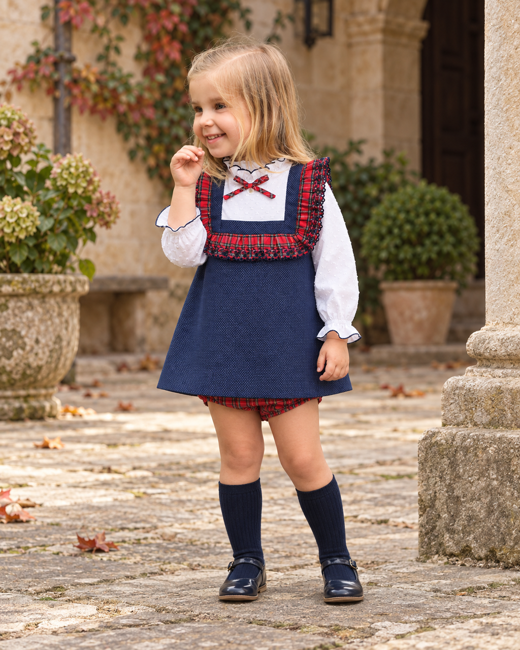 Foque Galletas girls navy tartan dress and knickers worn in a Spanish courtyard