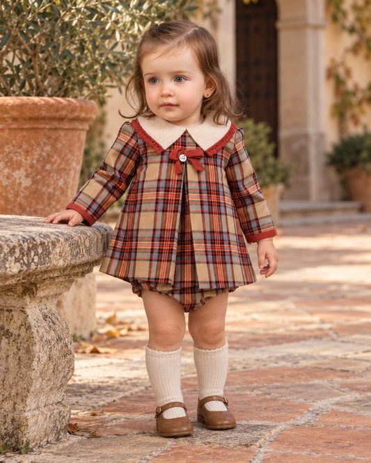 Baby girl wearing the Foque La Calabaza camel check dress and knickers in a Spanish courtyard