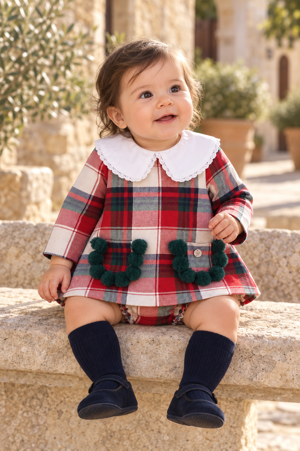 Baby girl wearing the Foque tartan pom-pom dress and knickers in Spain