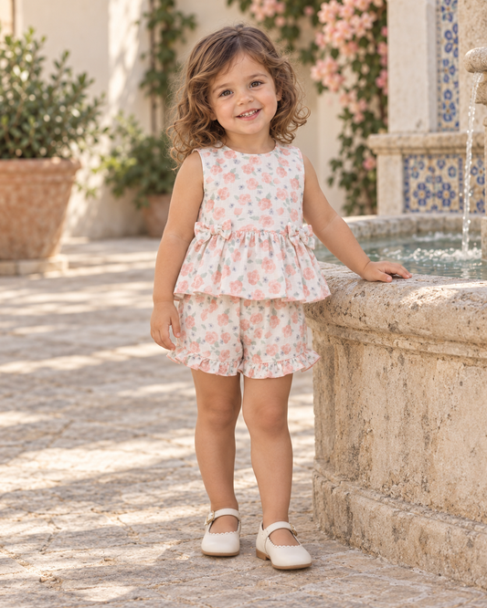 Girl wearing the Juliana Arandano peach rose floral peplum top and matching ruffle shorts in a Spanish courtyard