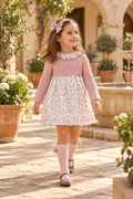 Girl wearing Juliana Arte powder pink knitted floral dress with matching pink pom pom socks