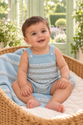 Baby boy wearing the Juliana Link knitted romper with coordinating blue and camel blanket