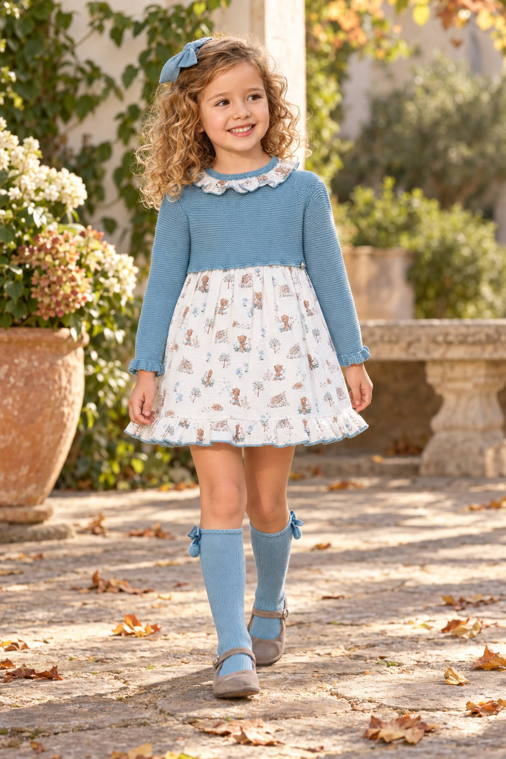 Girl wearing the Juliana Trazos blue knitted dress with matching blue pom-pom socks