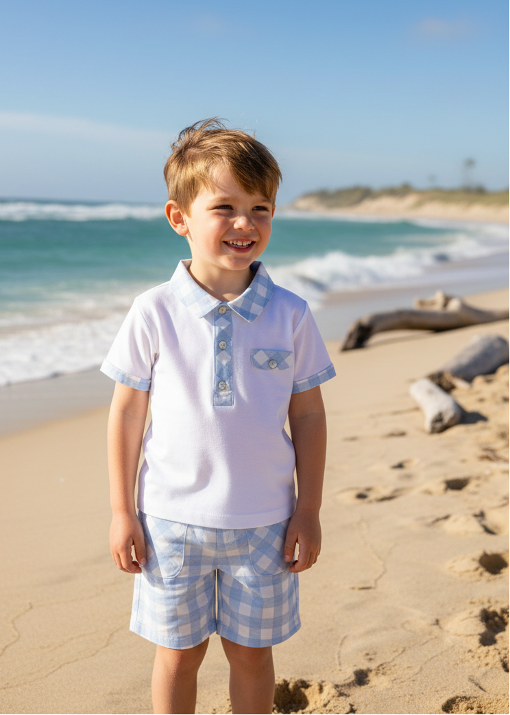 Little boy wearing white polo with gingham shorts at seaside
