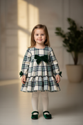 Little girl in cream and green tartan dress