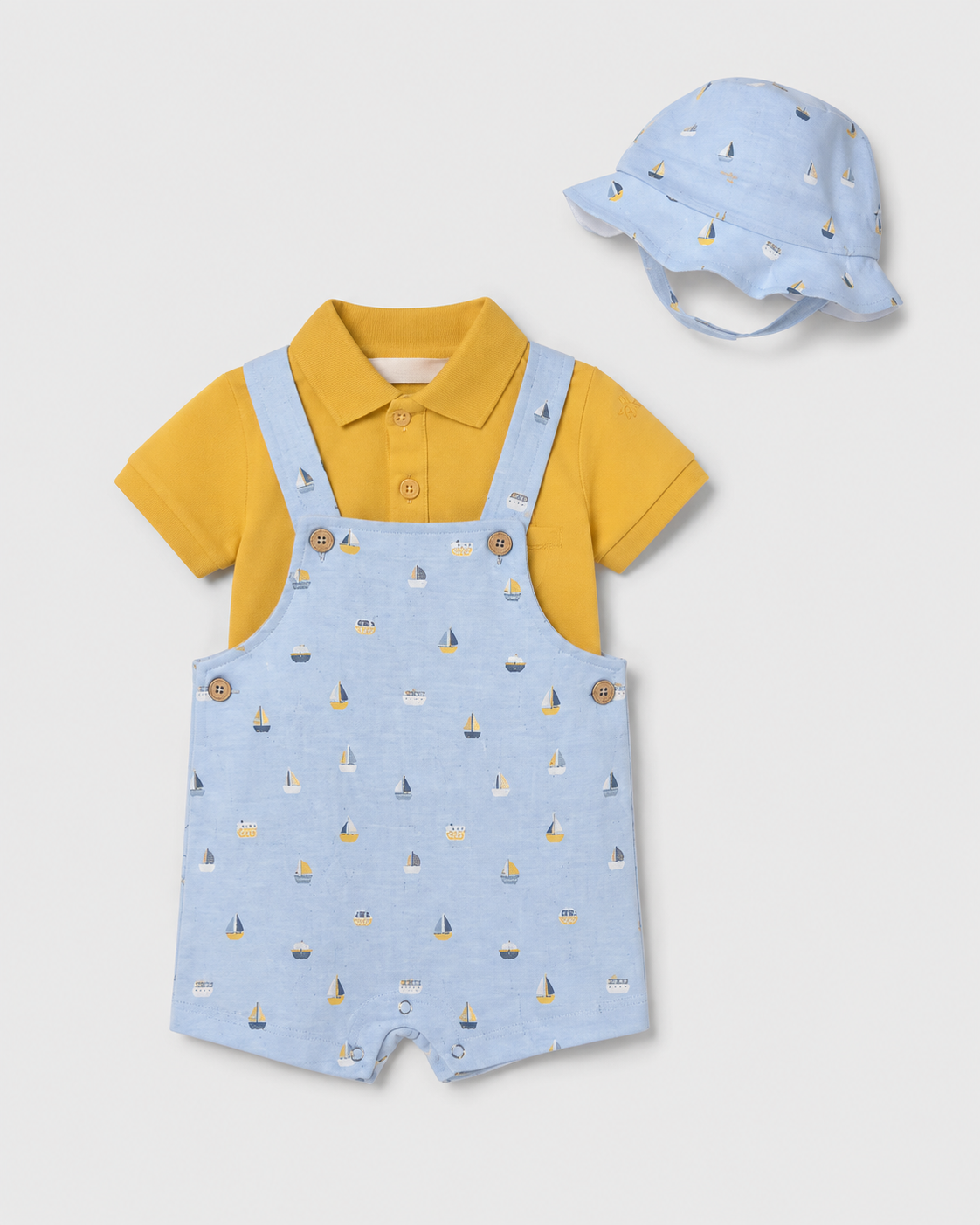 Flat lay of the Mayoral blue boat-print dungarees, mustard polo and matching sun hat
