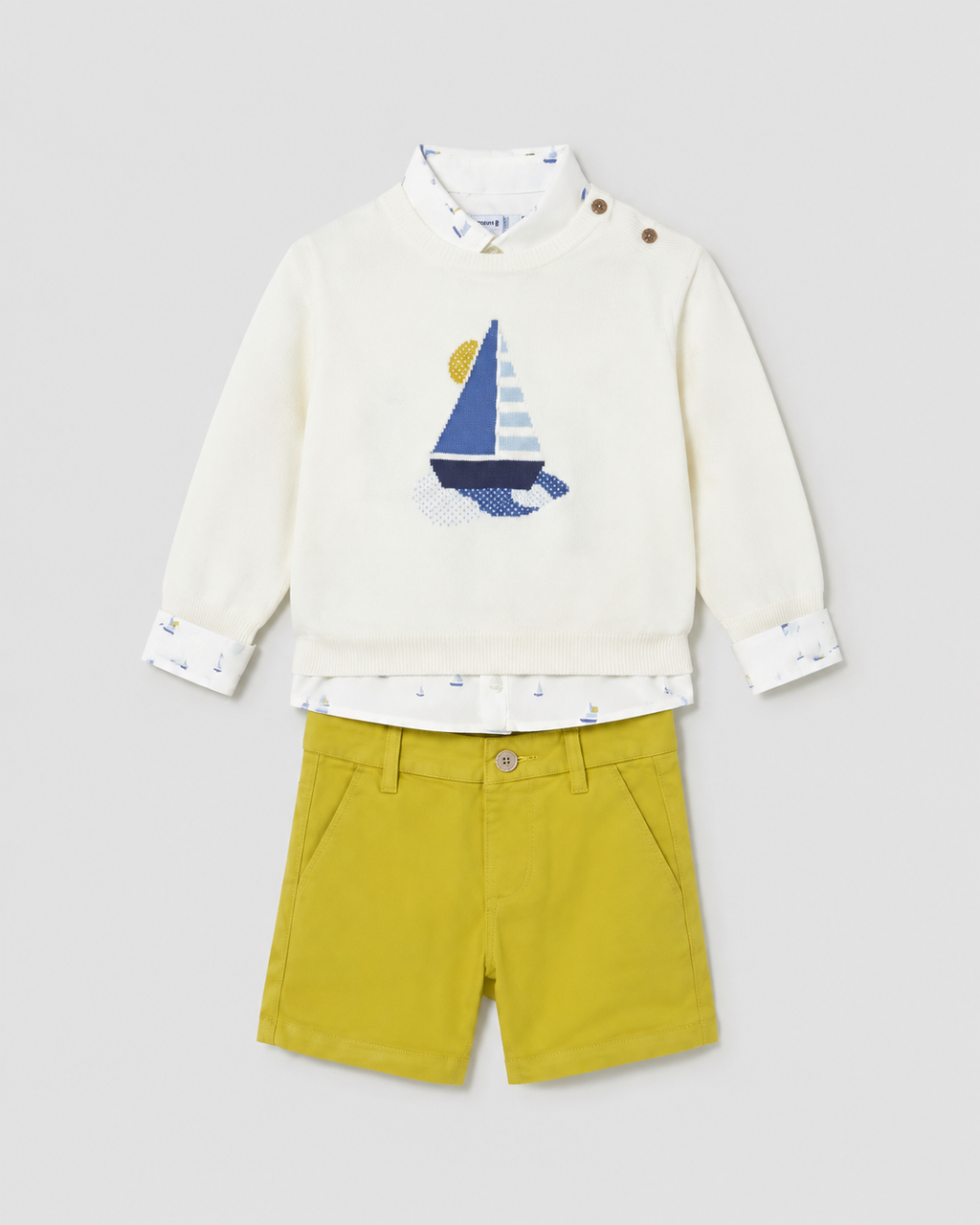 Flat lay of the Mayoral sailboat jumper, boat-print shirt and Capri-yellow shorts outfit