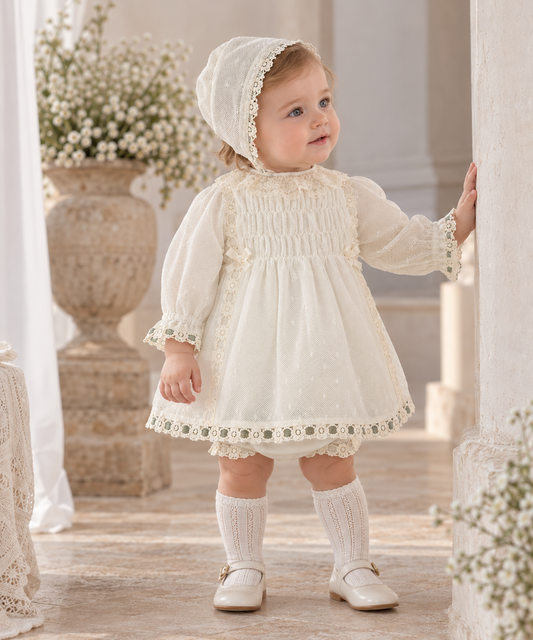 Baby girl wearing Miranda Ceremonia cream dress and delicate bonnet in Spanish style