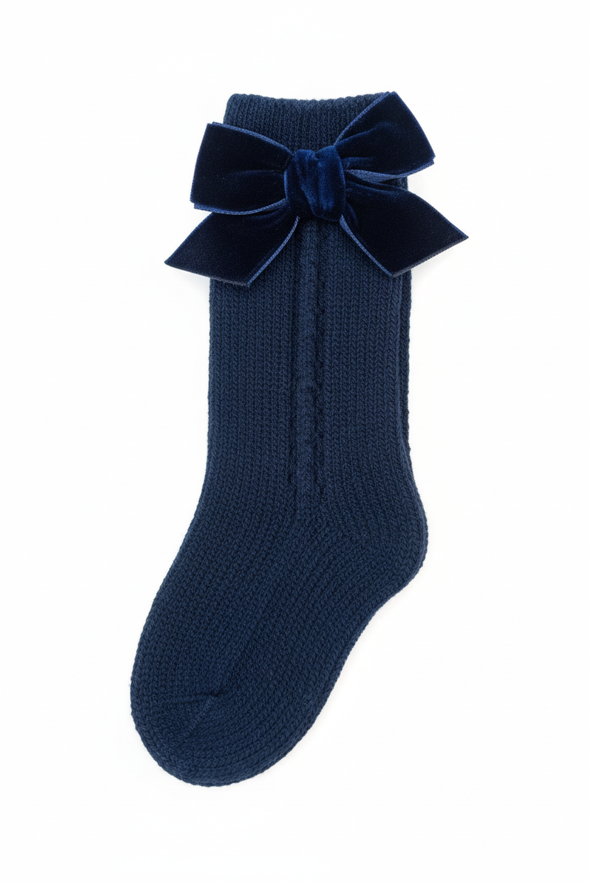 Navy blue cable knit knee-high sock with velvet bow on white background