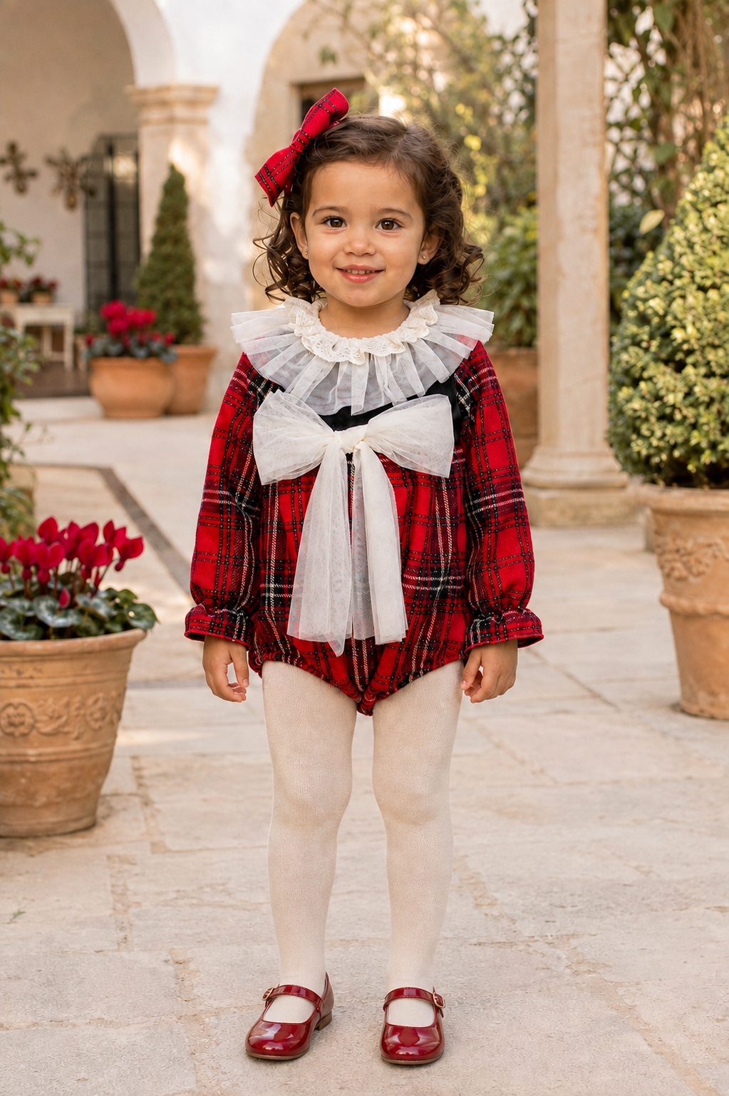 Little girl wearing the Naxos red tartan romper, full front view