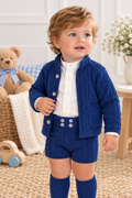 Toddler wearing Rahigo Oxford Blue Boys Three Piece Short Set with matching knee high socks in a soft nursery setting
